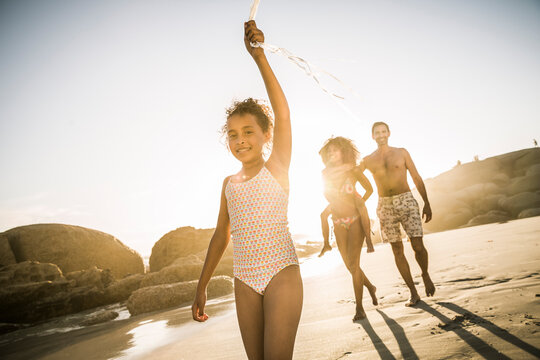 Happy girl with her family walking on the beach holding balloon string