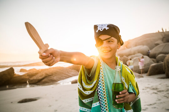 Boy dressed up as pirat on the beach at sunset