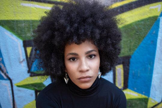 Young woman with blank expression against graffiti wall