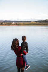 Fototapeta na wymiar Mother and son looking at lake, rear view