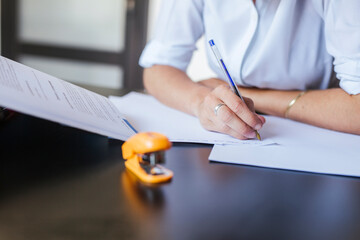 Close-up of female student learning at desk at home taking notes