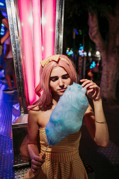 Portrait of a young woman with cotton candy on a funfair at night
