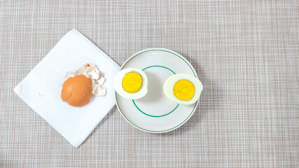 Two halves of a boiled egg on a plate, near which there is an eggshell.