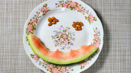 The eaten peel and bones from a watermelon on a plate in the form of a face.