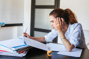 Frustrated female student with documents at desk at home