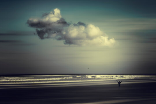 France, Nouvelle-Aquitaine, Contis, Clouds over silhouette of man standing on&Ocirc;&oslash;&Omega;Contis Plage beach with raised arms