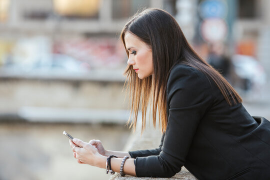 Serious woman leaning on a wall looking at mobile phone