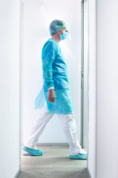 Mature male dentist walking in illuminated hallway at clinic