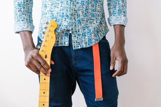 Male pop musician holding guitar fretboard against white background