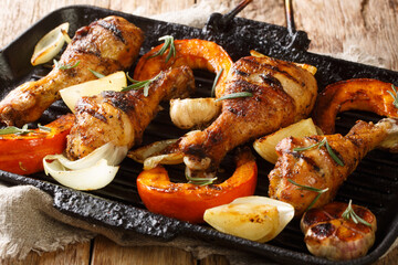 Healthy BBQ food grilled chicken legs with seasonal vegetables close-up in a grill pan on the table. horizontal