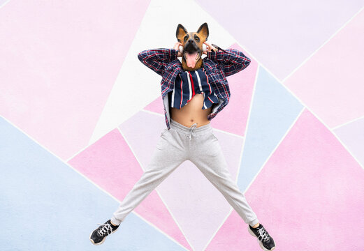 Playful woman wearing dog mask holding headphones while jumping against multi colored wall