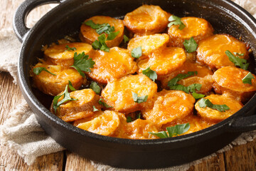 Hot delicious Spanish potatoes in a spicy sauce Patatas a la importancia close-up in a frying pan on the table. horizontal