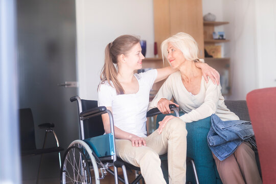 Daughter sitting in wheelchair embracing her mother