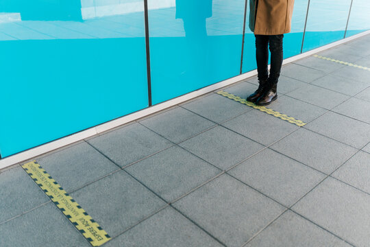 Man standing behind line of social distancing markings on footpath