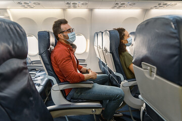 Man in a protective mask sleeping in an airplane seat while traveling with his family. Trip concept