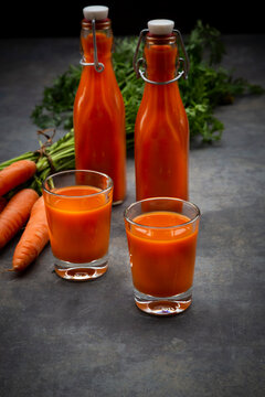 Carrot juice in bottles and glasses, bunch of carrots
