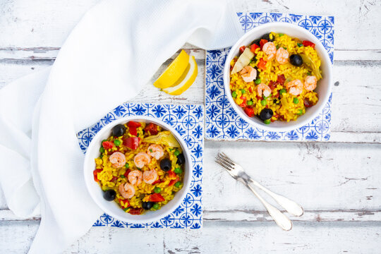 Paella with rice, bell pepper, tomato, artichoke, pea, black olive, curcuma and shrimps