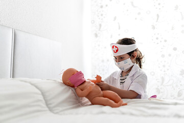 Girl in doctor's costume caring of her doll with a mask
