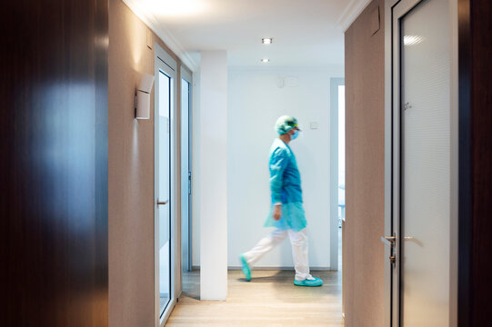Mature male dentist walking in illuminated hallway at medical clinic