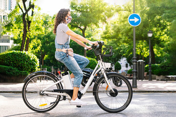 Woman riding electric bicycle on street during COVID-19