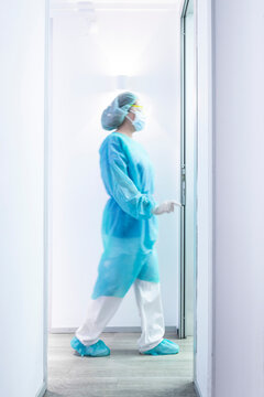 Mature female dentist walking in illuminated hallway