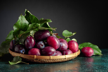 Purple plums with leaves.
