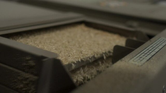 A rice mill shakes grains through a sifting process.