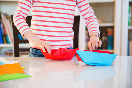 Close-up of girl tinkering with paper on table at home
