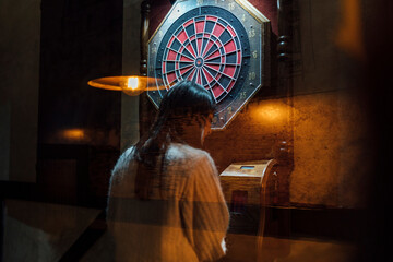 Young woman playing darts in bar