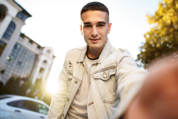 Portrait of young man taking a selfie while out on the city street, close up