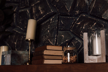 
A stack of books lies on a wooden shelf near the candles.