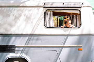 Girl looking through window while sitting in motor home