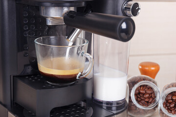 Making glass of tasty cappuccino in horn coffee maker.