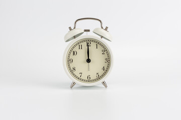 White retro clock alarm clock on white background shows 12:00 am or 12:00 pm or 00:00