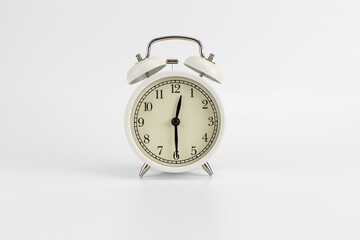 White retro clock alarm clock on white background shows 12:30 am or 12:30 pm or 00:30