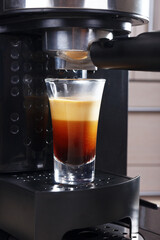 Making short glass of espresso in carob coffee maker.