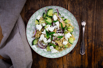 Plate of vegetarian salad with cucumbers, quinoa, feta cheese, red onions and mint