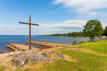 church cross on a rock on a lakeshore