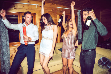 Cheerful friends with champagne bottles dancing and having fun in party