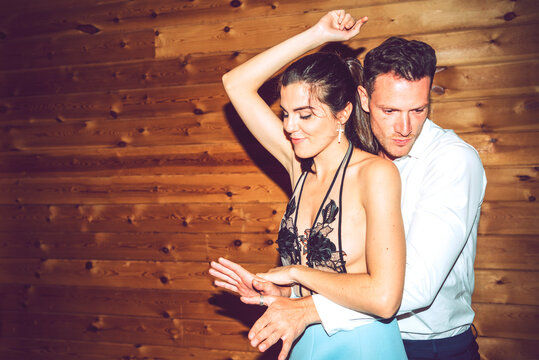 Young couple dancing against wooden wall in party