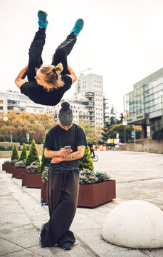Mam jumping over male friend using phone in city