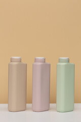Three bottles for cosmetics of different colors for soap, shower gel, shampoo, hair conditioner, on a beige background