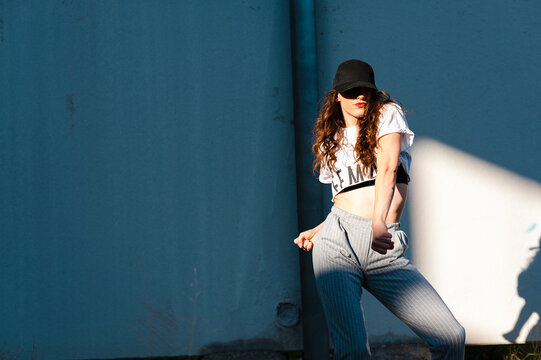 Female hip-hop dancer puckering lips while dancing against white wall during sunny day