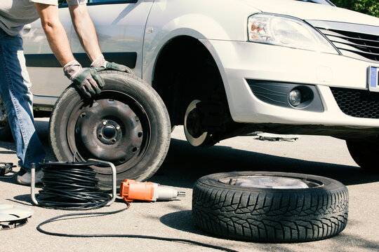Man changing car tires, partial view