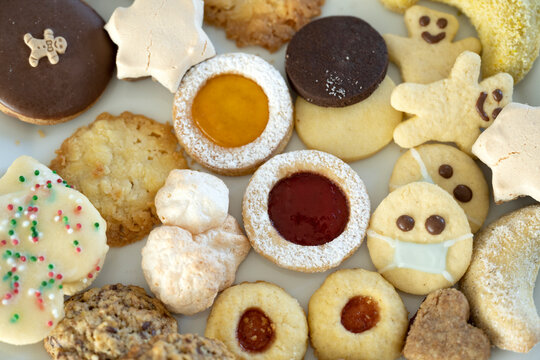 Various ready-to-eat Christmas cookies, one wearing protective face mask