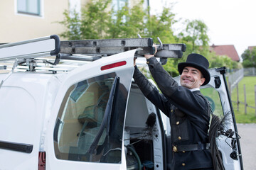 Portrait of smiling chimney sweep at his van