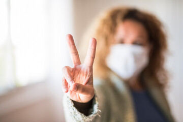 Woman with face mask making victory sign