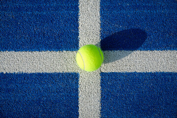 Yellow tennis ball in the court on blue grass - Paddle tennis ball on the court on blue turf