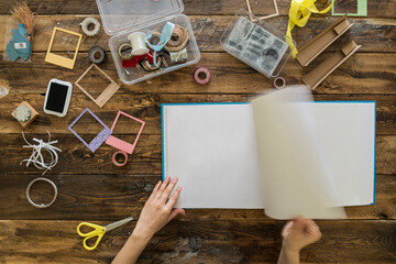 Top view of woman's hands preparing a scrapbook