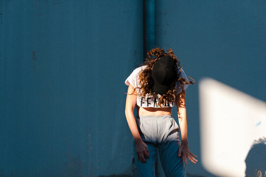 Female hip-hop dancer dancing against white wall during sunny day